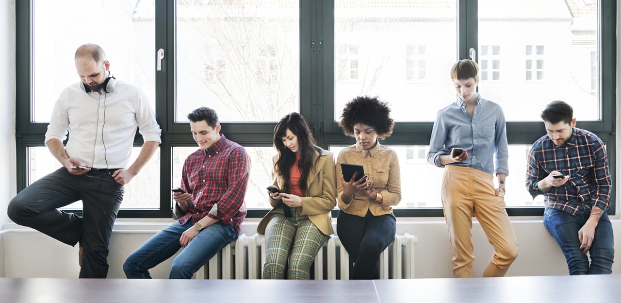 A row of people all looking at their mobile devices