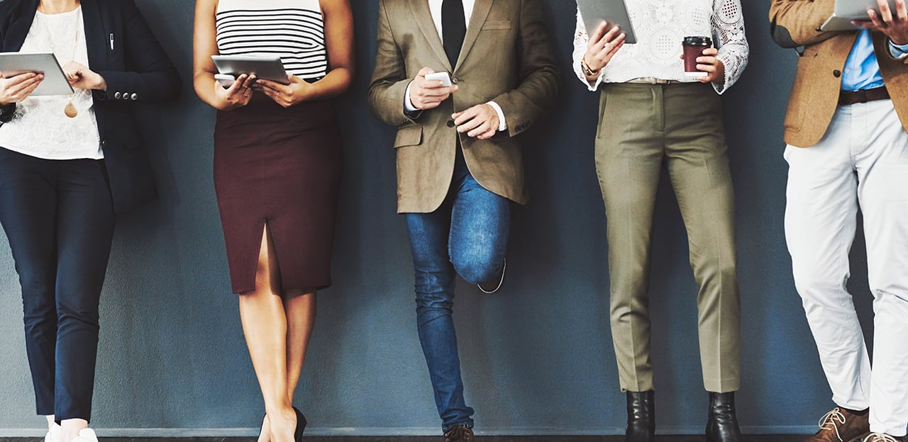 A row of people from the shoulders, down, viewing various mobile devices