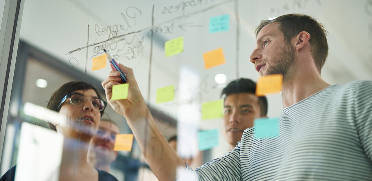 People using a glass panel like a whiteboard during a business meeting